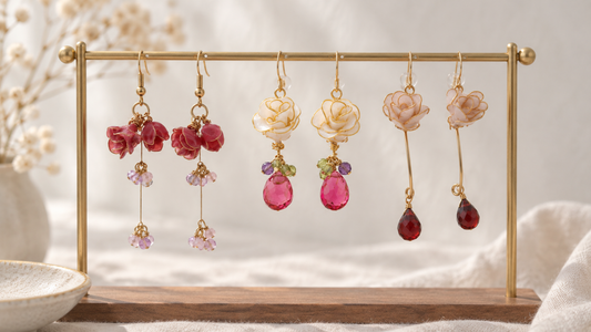 Handmade floral earrings hanging on a gold display stand in a soft natural light setting